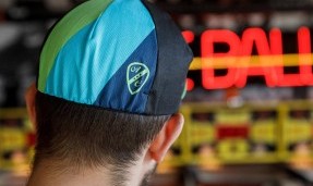 Person wearing Black, blue, and green All-City Cycles Interstellar Cycling Cap
