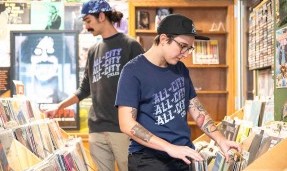 Person wearing Blue All-City flow motion t-shirt in record store