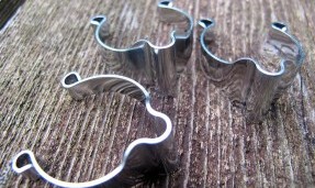 Two polished silver All-City Cable Clamps on wood background 