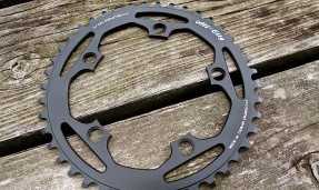 Black All-City cycles Cross Chainring on wood background top view 