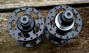 Two polished black All-City New Sheriff SL Rear hubs on wood background