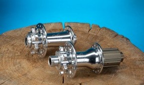 Polished Silver All-City Cycles Go-Devil Rear Disc Hub on brown table with blue background