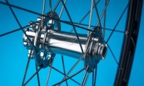 polished silver all city go devil front disc hub shown on bike wheel against blue background