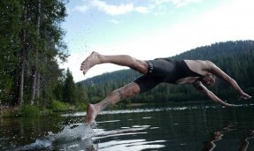 Person wearing black perennial bibs diving into a lake