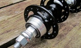 Black and silver All-City Standard 130 Rear hub on wood background, side view