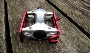 all city red and polished silver standard track pedal against wood background