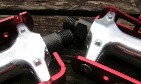 close up view of Two all city red and polished silver standard track pedals against wood background