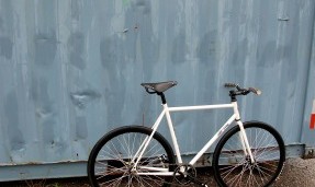 Black and white All-City cycles Star Track grips on white bike against blue wall