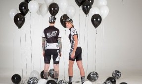 Two people showing their backs while wearing All-City black and white Wangaaa jersey with black and white balloons around them 