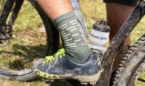 Person's foot on a pedal wearing army green and tan All-City team space horse socks