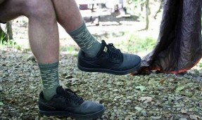 Person with crossed legs wearing army green and tan All-City team space horse socks 