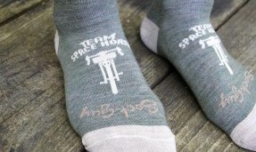 Persons feet close up wearing army green and tan All-City team space horse socks 