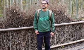 Person wearing a green throwback crewneck sweatshirt with outdoor wall background