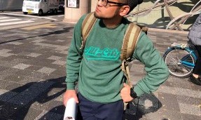 Person wearing a green throwback crewneck sweatshirt with outdoor background