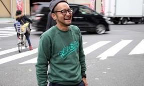 Person wearing a green throwback crewneck sweatshirt while crossing cross walk