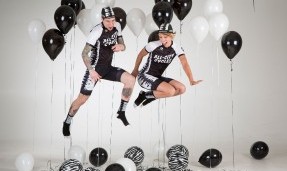 Two people jumping while wearing All-City black and white Wangaaa Bibs with black and white balloons around them 