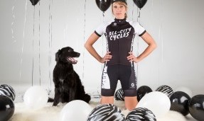 A person and a black do posing while wearing All-City black and white Wangaaa jersey with black and white balloons around them