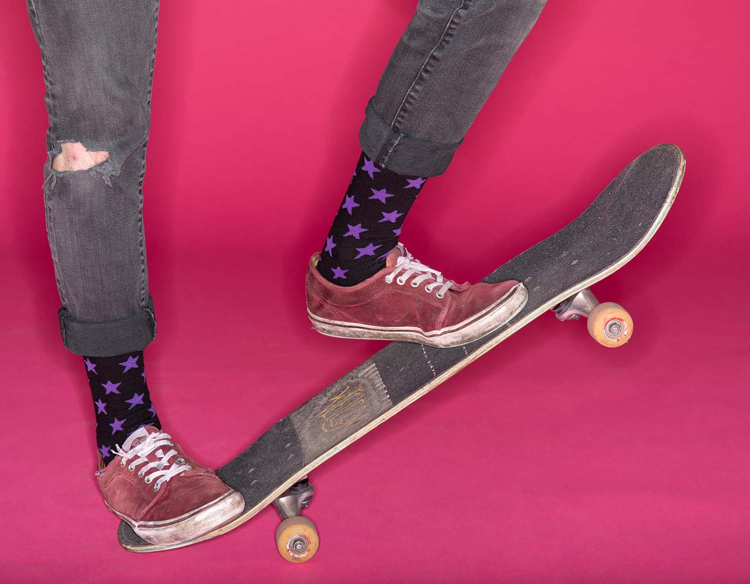 Person wearing black let's Go Crazy Socks while skateboarding on pink background
