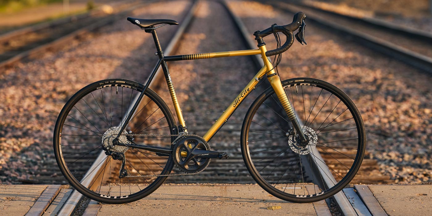 All-City Zig Zag 105 Bike in Golden Leopard paint scheme on railroad crossing