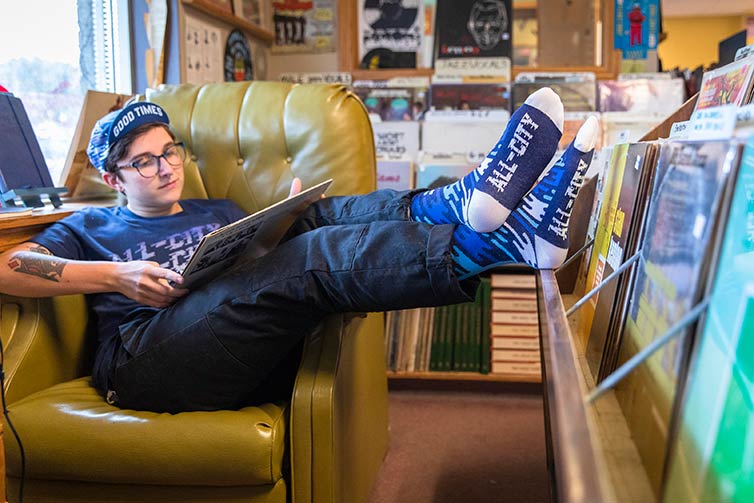 A person lounging in Flow Motion socks, t-shirt and hat